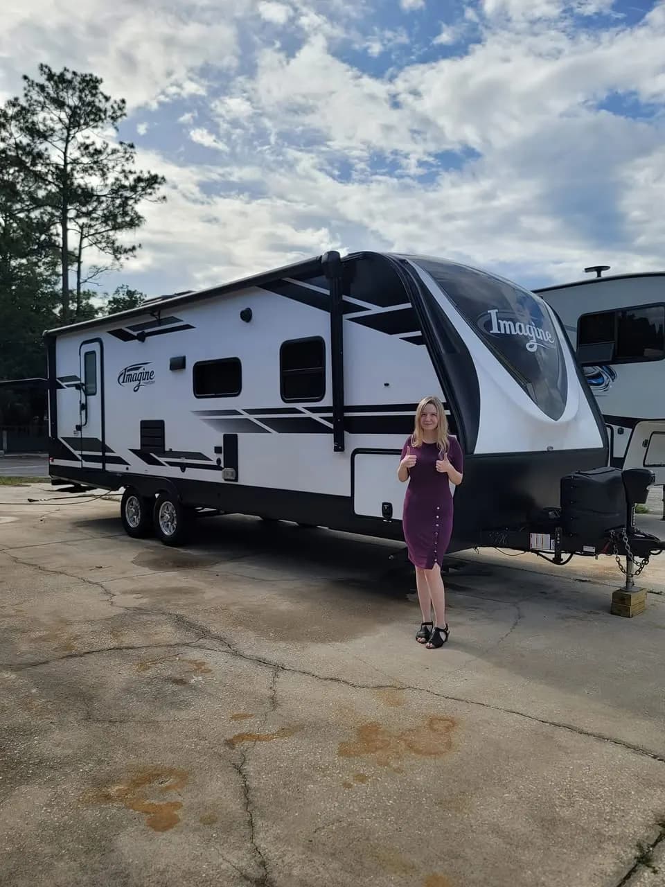 Customer giving a double thumbs-up in front of her Grand Design Imagine travel trailer
