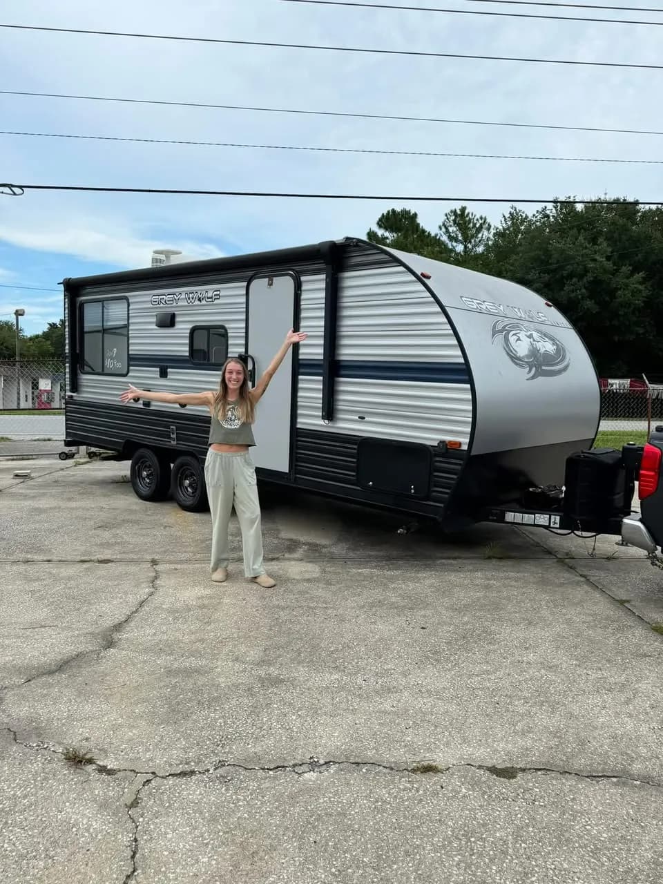 Young customer celebrating in front of her Forest River Grey Wolf travel trailer
