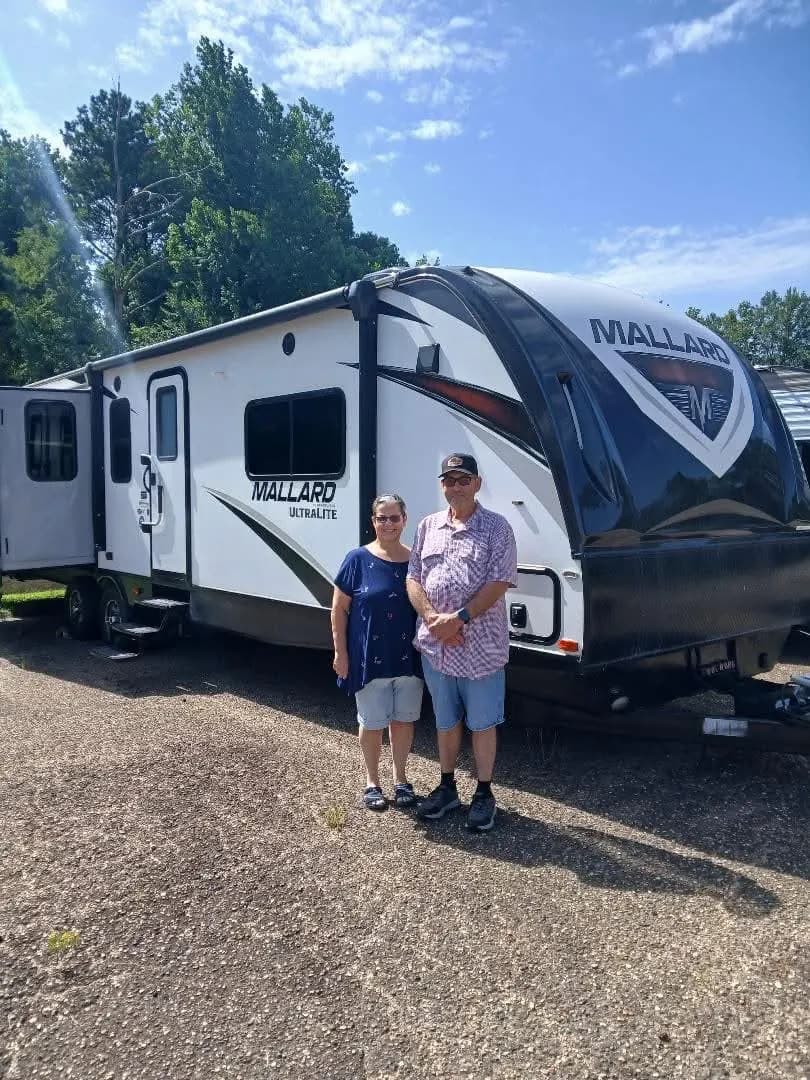 Couple in front of their Heartland Mallard Ultralite travel trailer