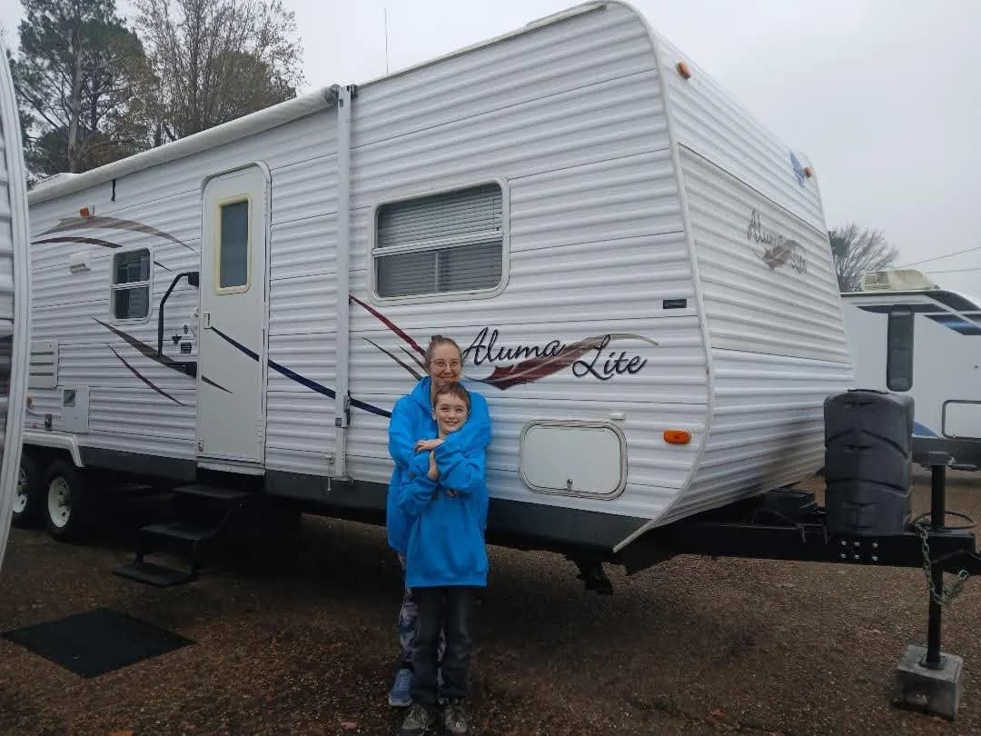 Mother and son hugging in front of their Aluma Lite travel trailer