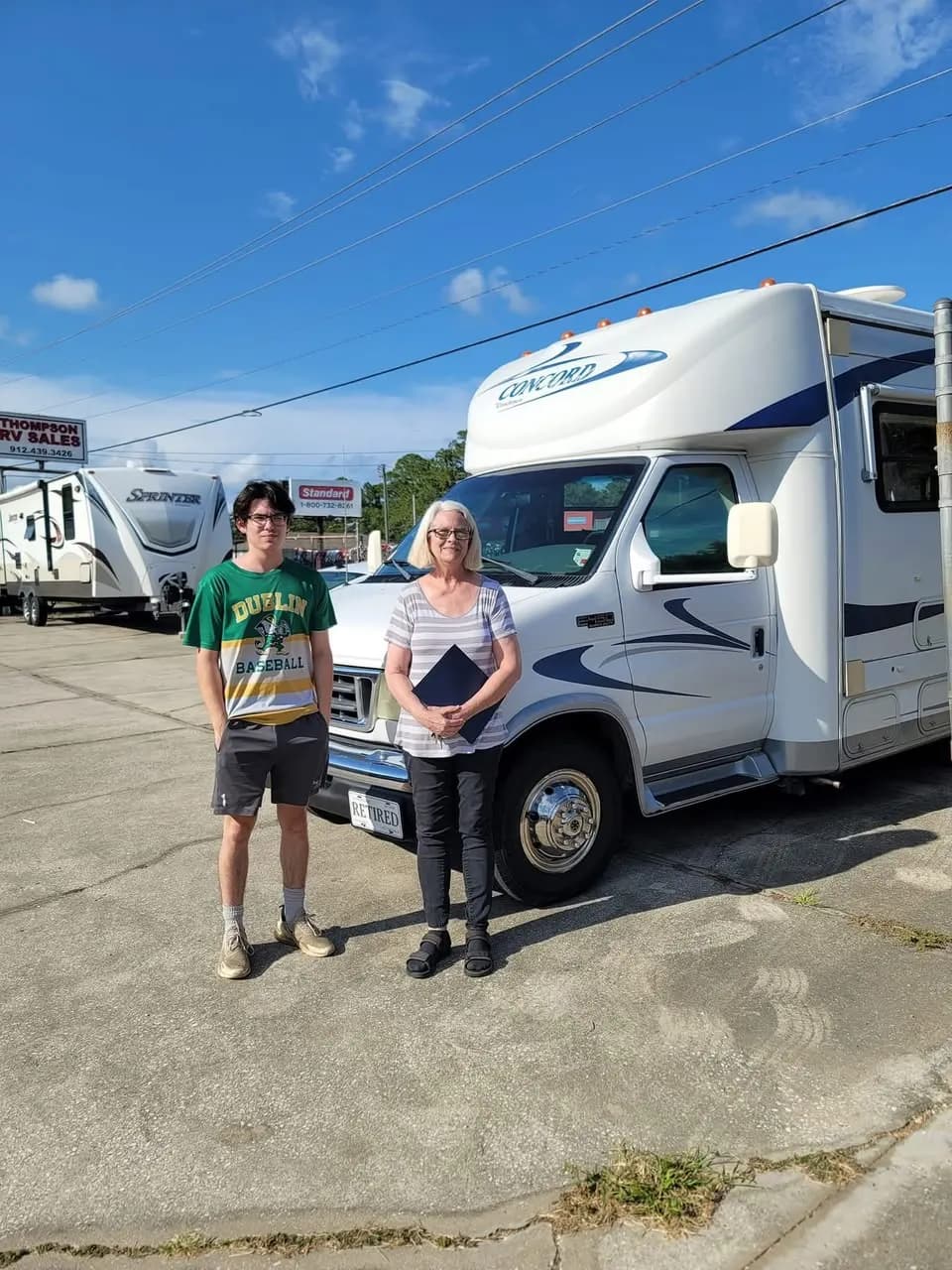 Grandmother and grandson with paperwork by their Coachmen Concord motorhome
