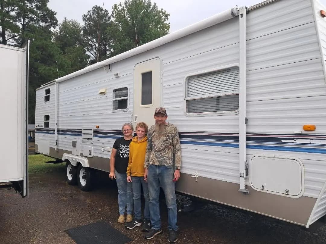 Family in front of their travel trailer on delivery day