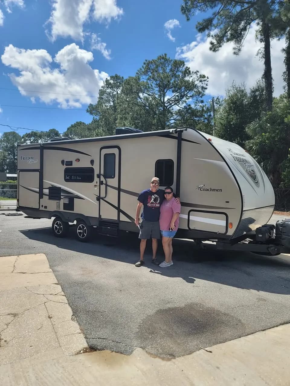 Couple in front of their Coachmen Freedom Express travel trailer