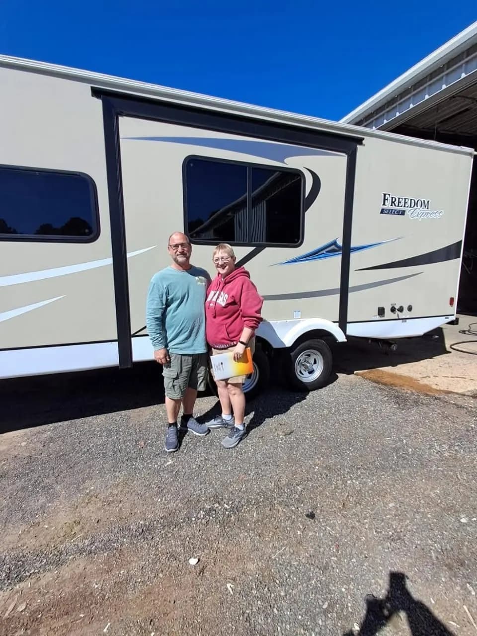 Couple in front of their Coachmen Freedom Express Select travel trailer